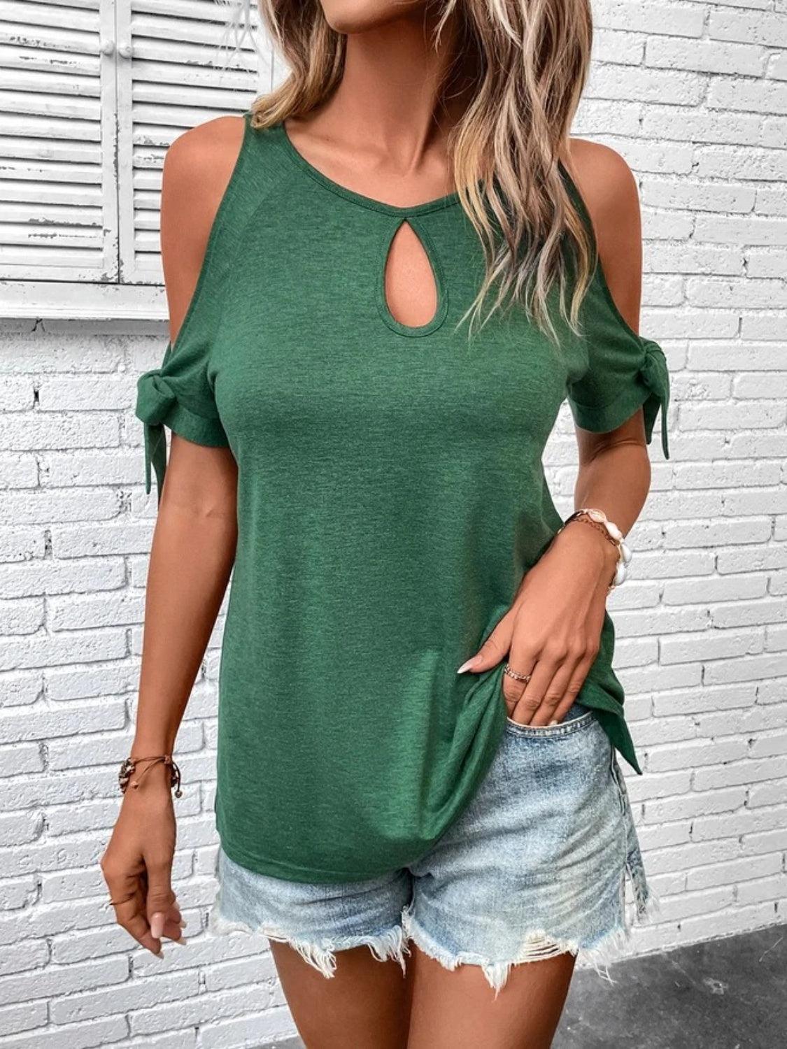 a woman wearing a green top with a cut out shoulder