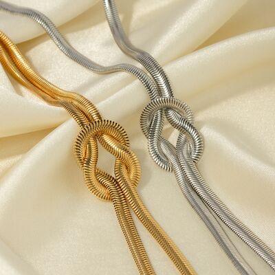 a close up of a gold and silver necklace on a white cloth