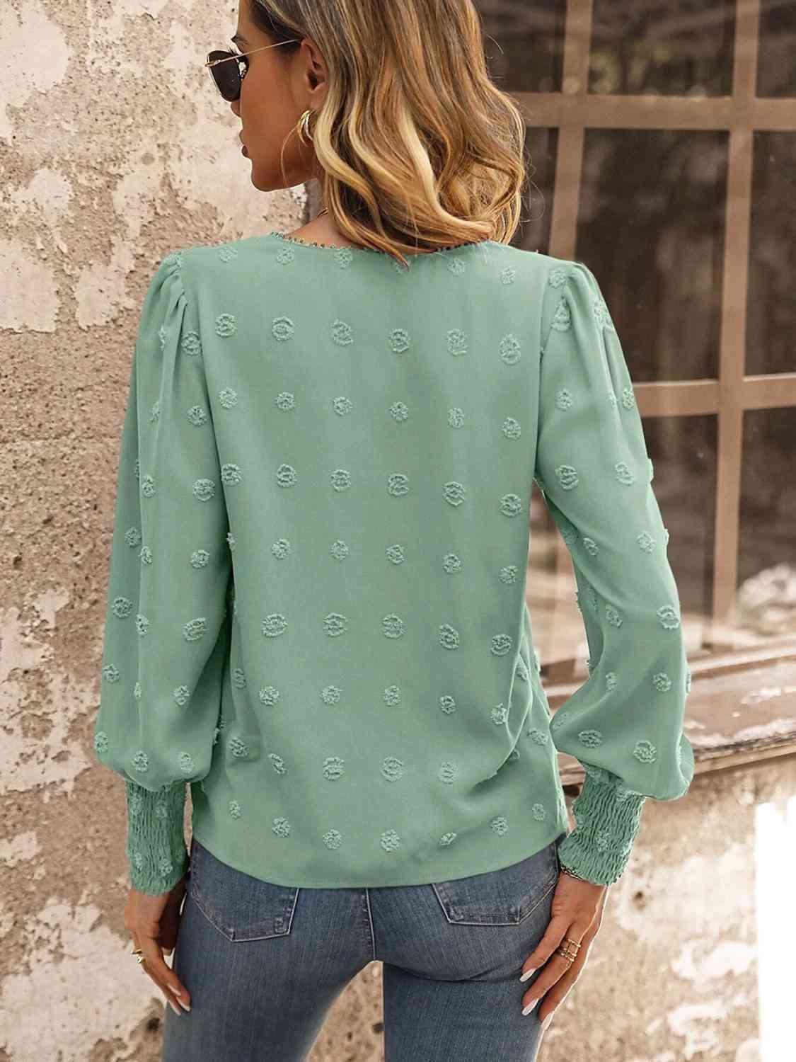 a woman wearing a green blouse and jeans