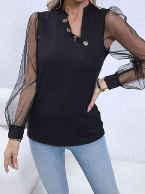 a woman wearing a black top with sheer sleeves