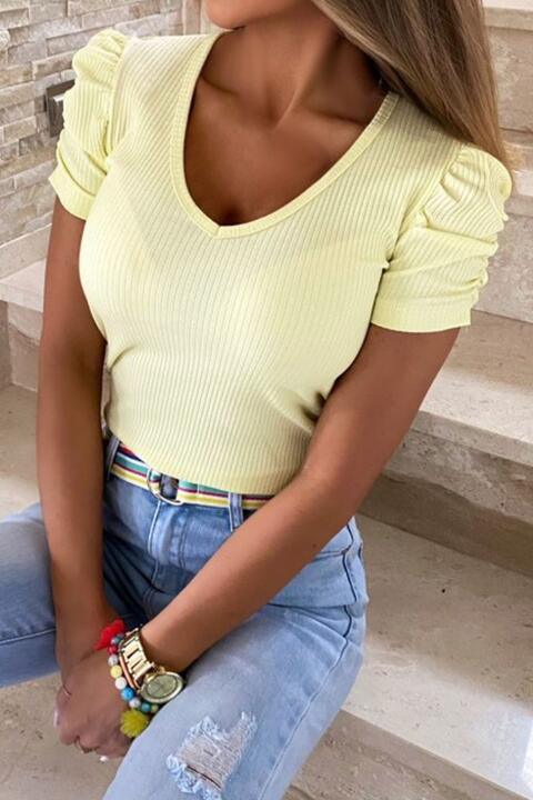 a woman sitting on some steps wearing a yellow top