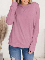 a woman wearing a pink sweater and ripped jeans