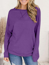 a woman wearing a purple sweater and jeans