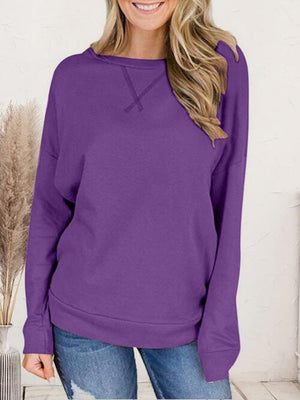 a woman wearing a purple sweater and jeans