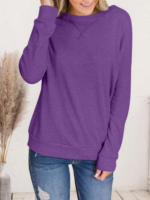 a woman wearing a purple sweater and ripped jeans