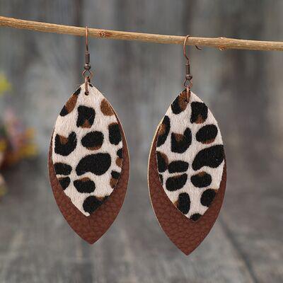 a pair of leopard print leather earrings hanging from a branch