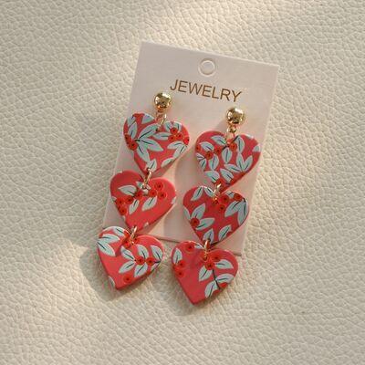 a pair of heart shaped earrings sitting on top of a white surface