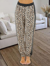 a woman standing in front of a couch wearing leopard print pants