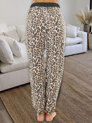 a woman standing in front of a couch wearing leopard print pants