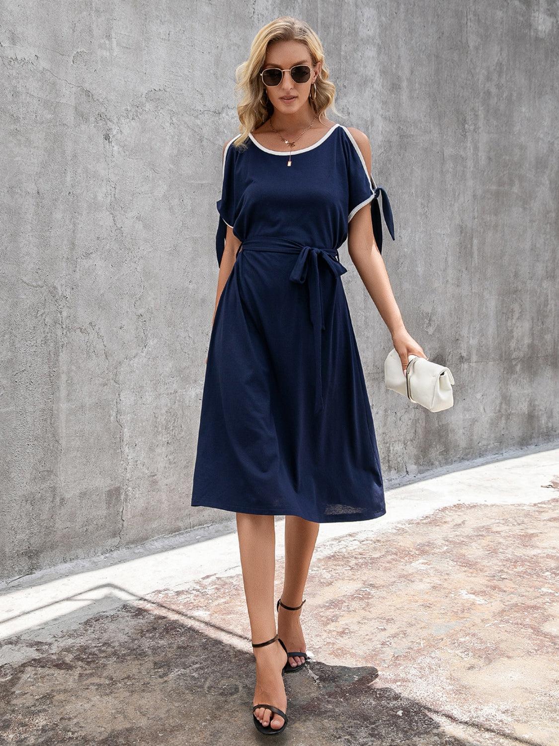 a woman in a blue dress is holding a white purse