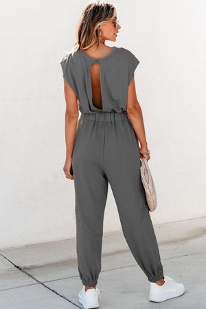 a woman wearing a grey jumpsuit and white sneakers