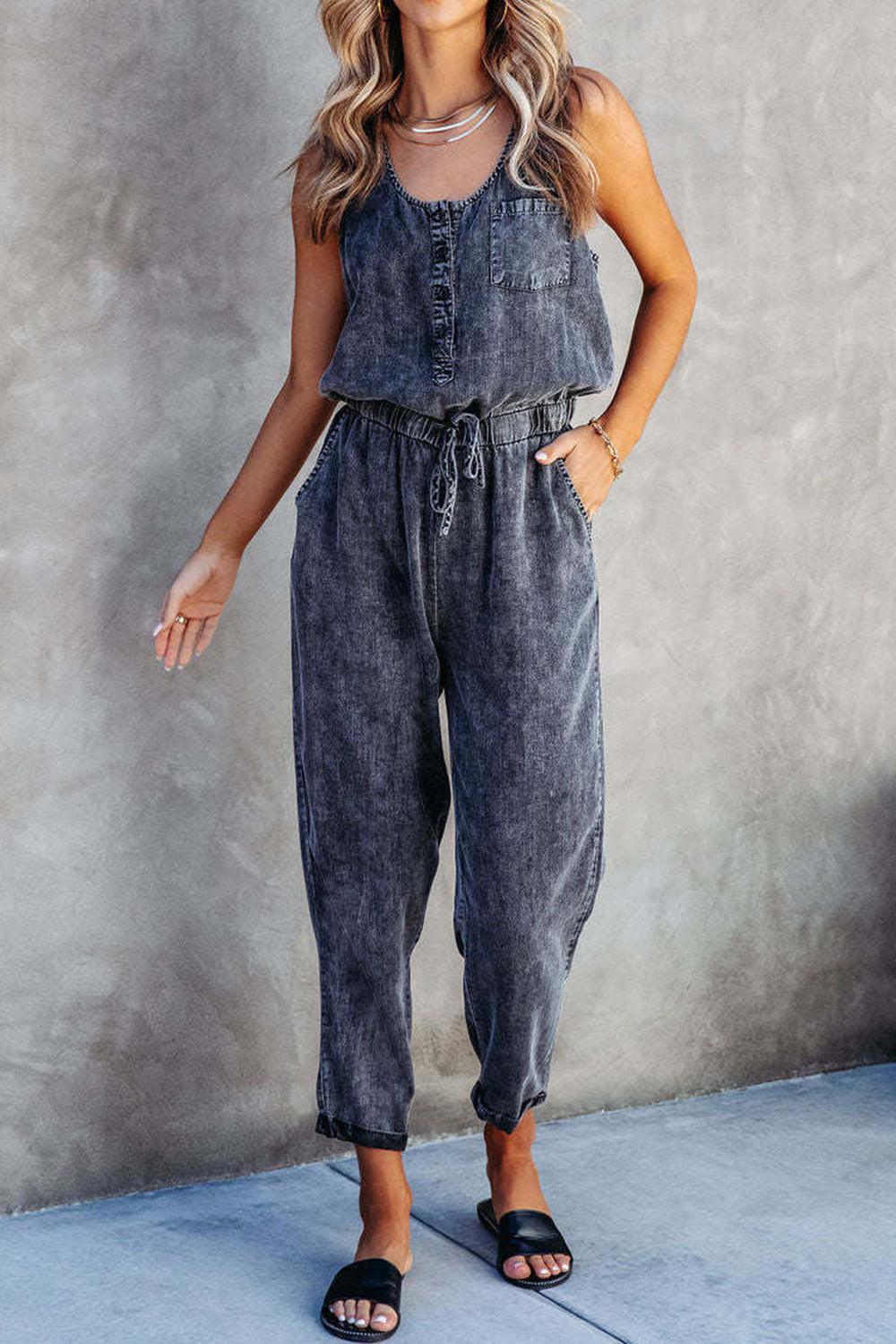 a woman standing in front of a wall wearing a denim jumpsuit