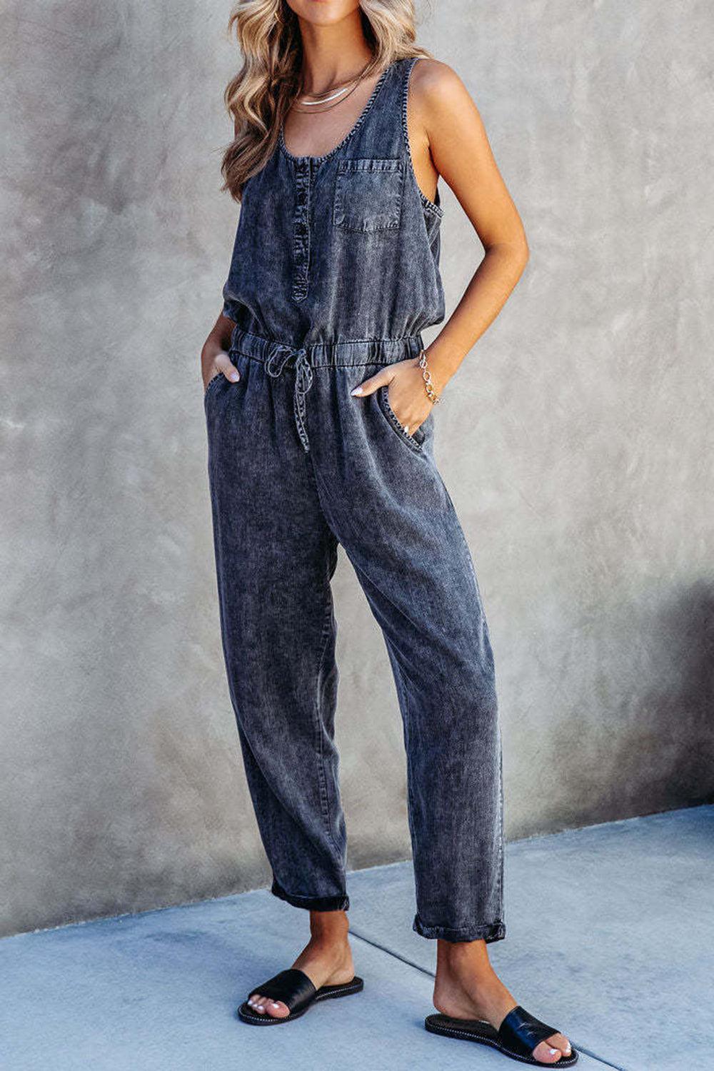 a woman standing in front of a wall wearing a denim jumpsuit