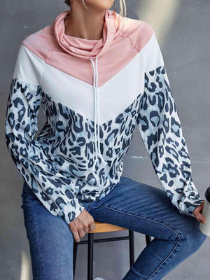 a woman sitting on a stool wearing a leopard print hoodie