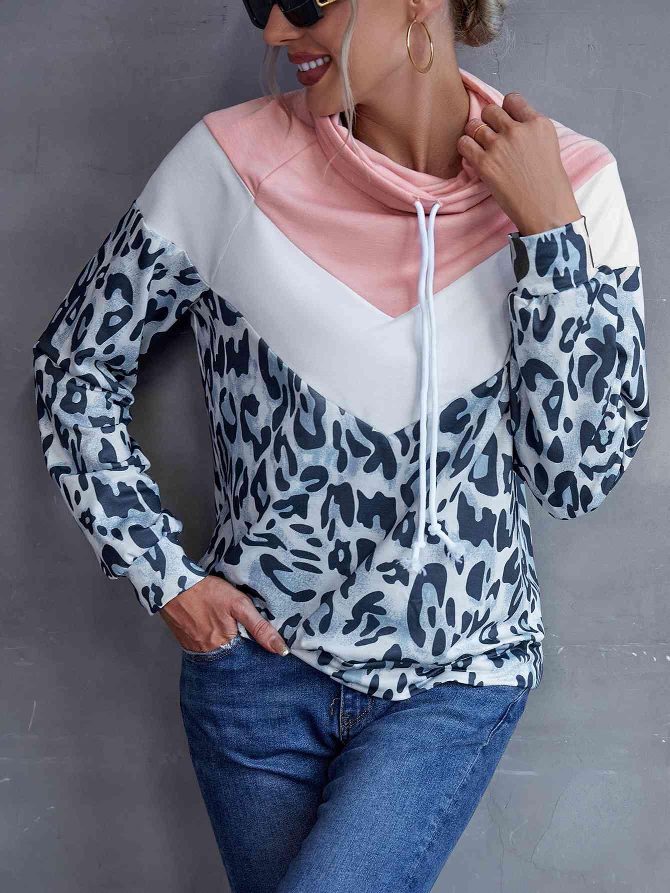 a woman wearing a leopard print hoodie and jeans