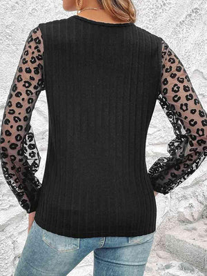 a woman wearing a black sweater with leopard print sleeves