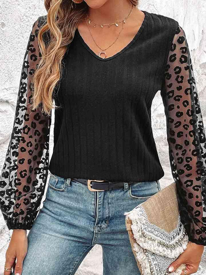 a woman wearing a black top with leopard print sleeves