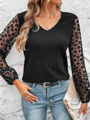 a woman wearing a black top with leopard print sleeves