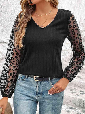 a woman wearing a black top with leopard print sleeves