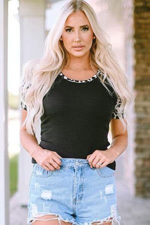 a woman wearing a black shirt and denim shorts