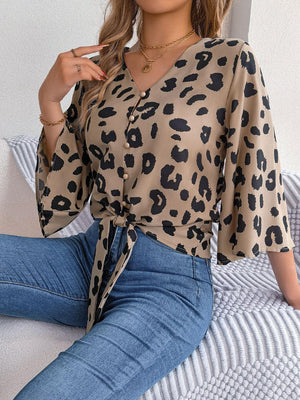 a woman sitting on top of a bed wearing a leopard print shirt