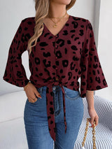 a woman wearing a leopard print shirt and jeans