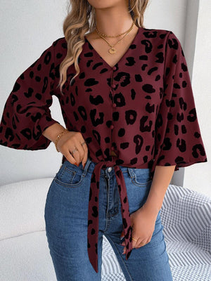 a woman wearing a leopard print blouse and jeans