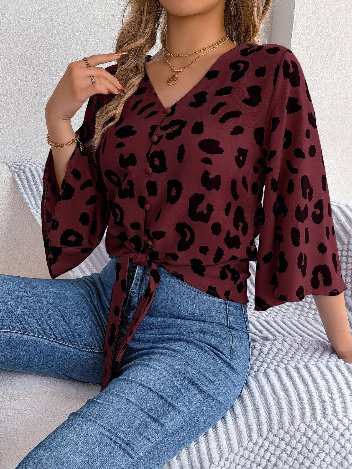 a woman sitting on a bed wearing a leopard print top