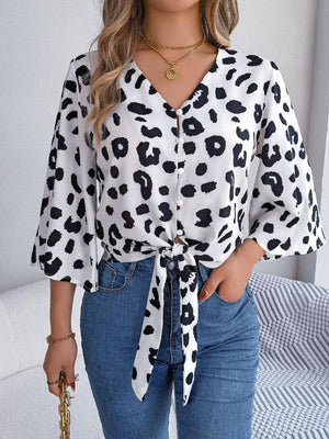 a woman wearing a leopard print shirt and jeans