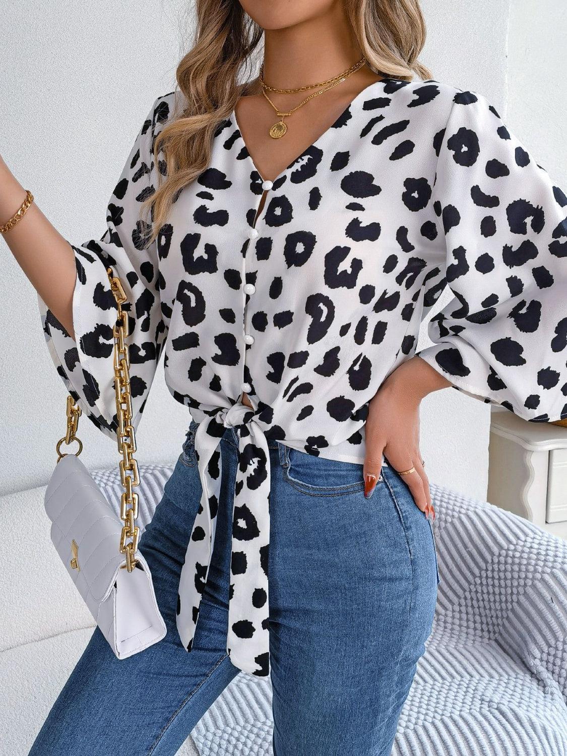 a woman wearing a leopard print blouse and jeans