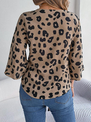 a woman standing in front of a couch wearing a leopard print top