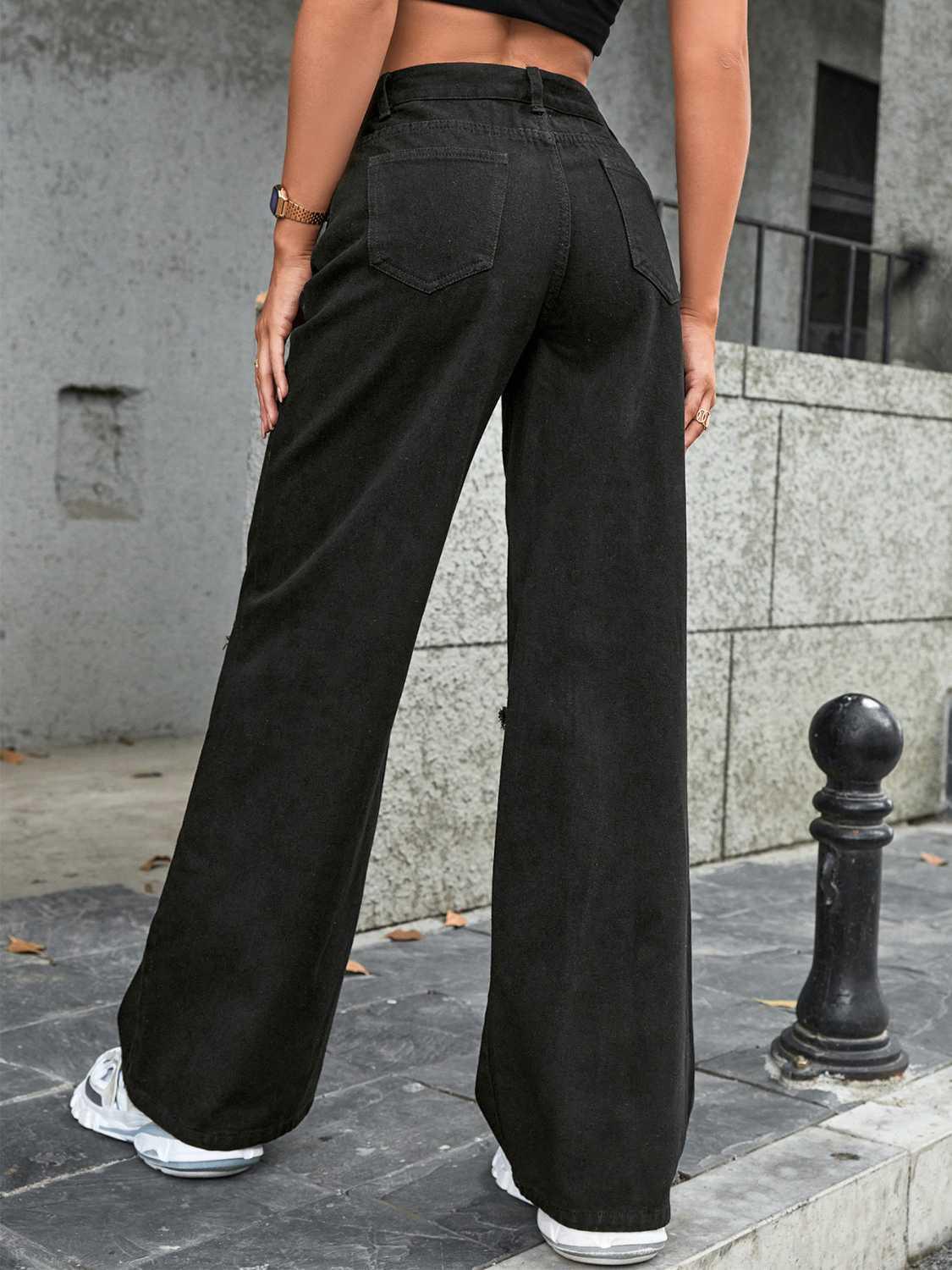 a woman in a crop top and wide legged black pants