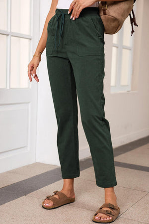 a woman wearing green pants and a white shirt