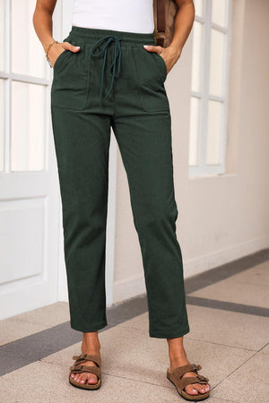 a woman standing in front of a door wearing green pants