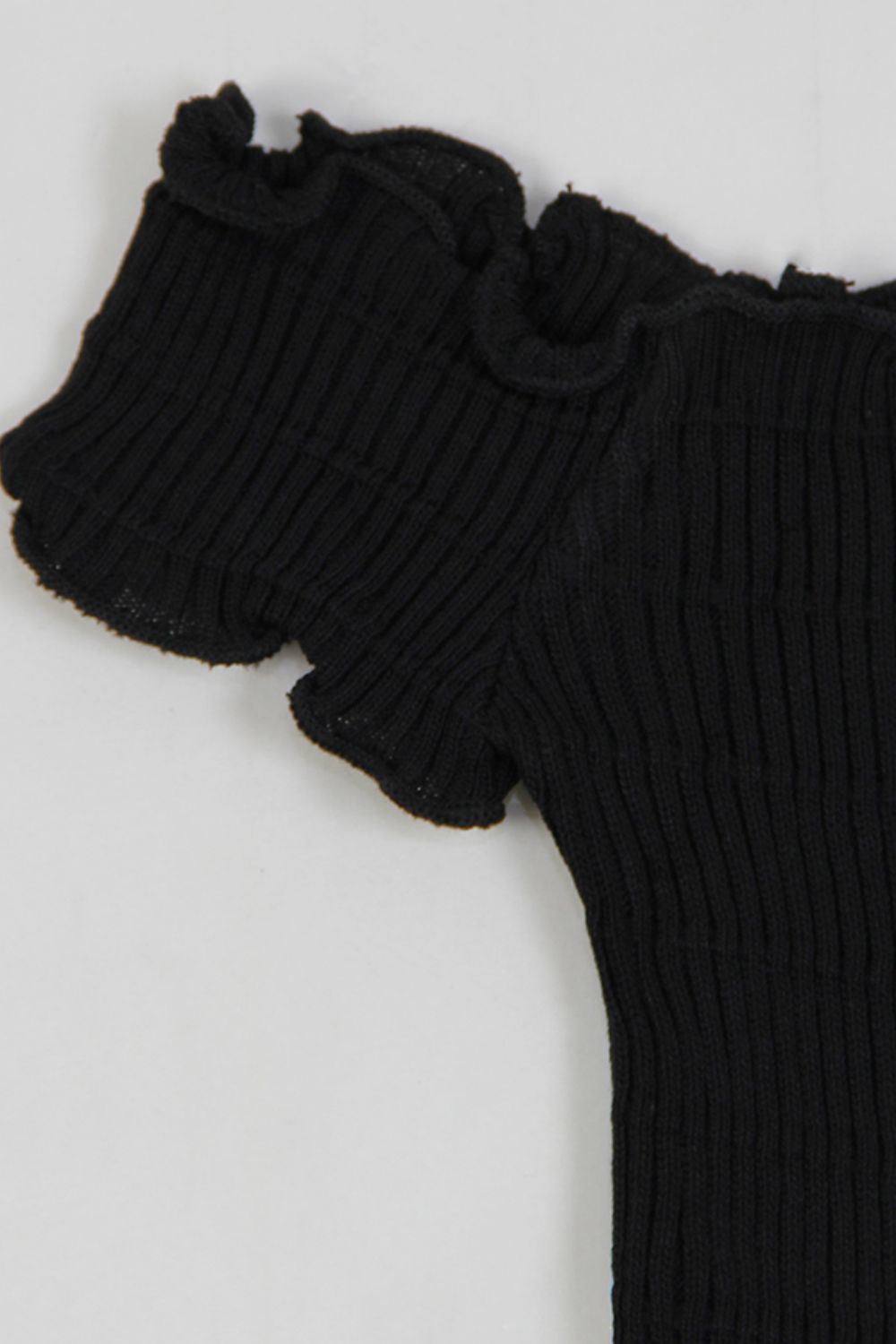 a teddy bear wearing a black sweater with ruffles