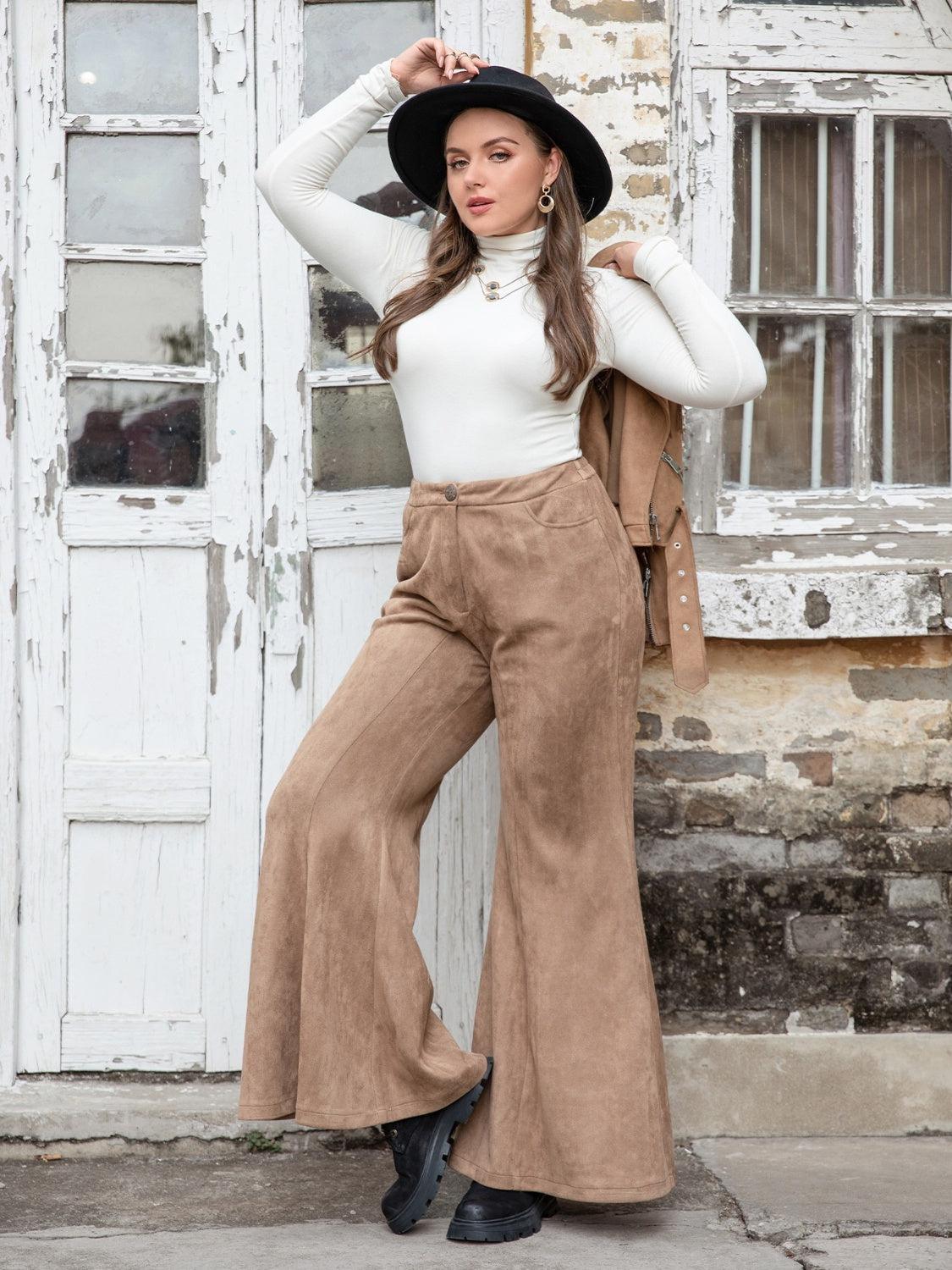 a woman wearing wide legged brown pants and a black hat