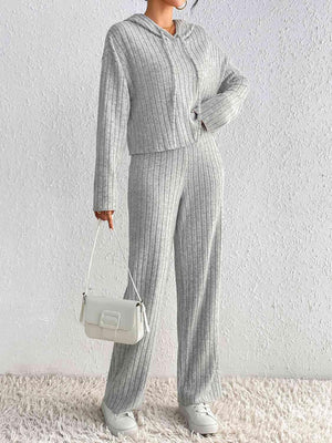a woman in grey sweater and pants holding a white purse