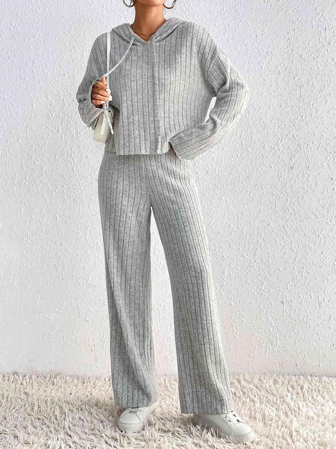 a woman wearing a grey sweater and wide legged pants