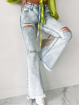 a woman wearing ripped jeans and a green top