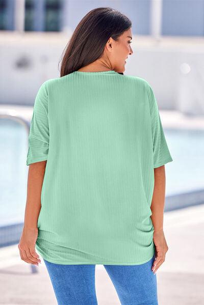 a woman standing in front of a pool wearing a green top