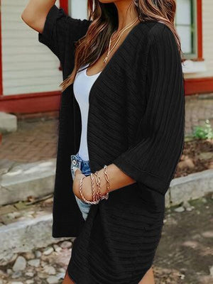 a woman wearing a hat and a black cardigan