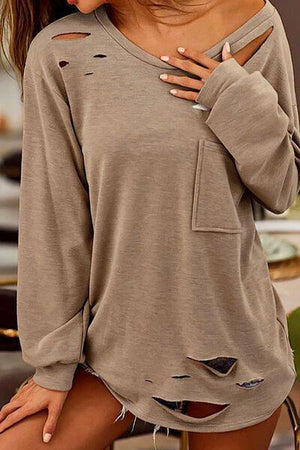 a woman wearing a grey shirt with holes on it