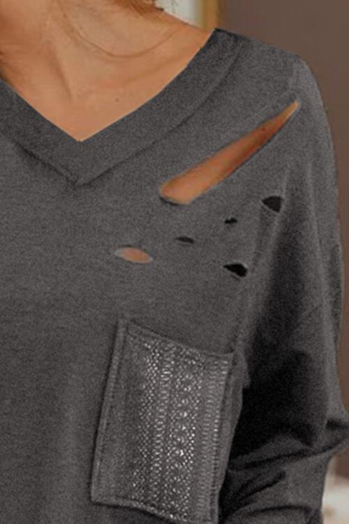 a woman wearing a gray shirt with holes on it