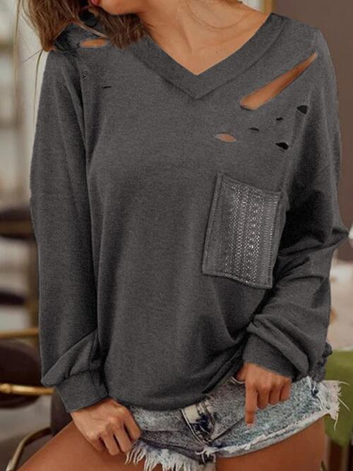 a woman wearing a grey sweater with holes on it