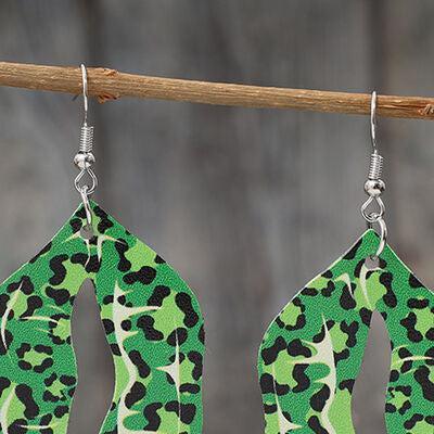 a pair of green and black earrings hanging from a wooden stick