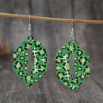 a pair of green and black earrings hanging from a wooden stick