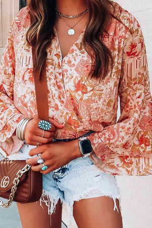 a woman wearing a floral blouse and denim shorts