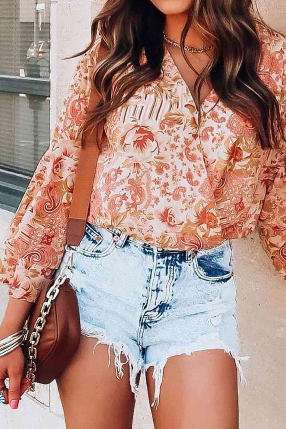 a woman wearing a floral blouse and denim shorts