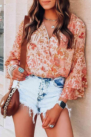 a woman wearing a floral blouse and denim shorts