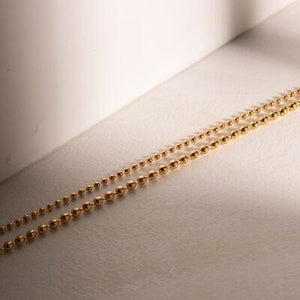 a chain of gold beads on a white surface
